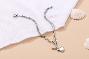 Detailed macro view of silver guitar pendant on double-layer stainless steel chain