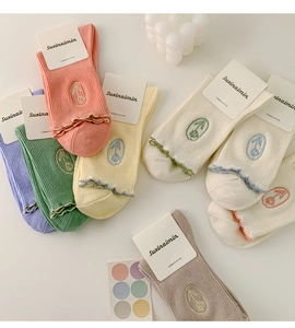 Flat lay of colorful combed cotton socks with floral embroidery and wavy lace trim edges