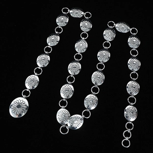 Silver metal chain belt for women featuring engraved oval sunburst medallions on black background