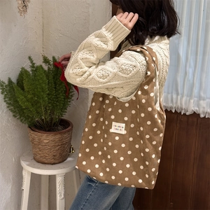 Detail of brown polka dot corduroy tote bag showing soft ribbed texture and label