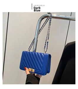 Detail of deep blue quilted leather bag with golden twist lock and chain strap