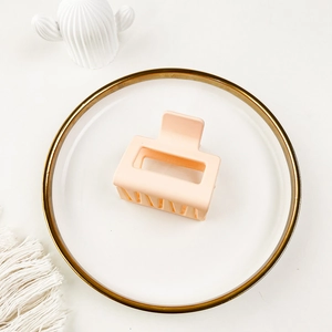 Detail of a matte light pink square hair claw clip with a hollow minimalist design
