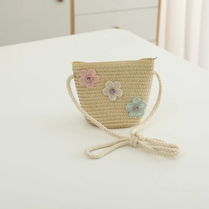 Détail du sac en paille beige avec fleurs en dentelle et bandoulière en corde tressée