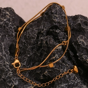 Macro detail of 18K gold-plated double-layer snake chain with square beads on stone