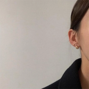 Gros plan sur les boucles d'oreilles feuille d'or et créoles huggie sur un mannequin