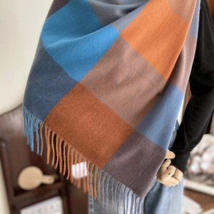 Plaid cashmere-like shawl scarf with tassels on mannequin in cozy warm indoor setting