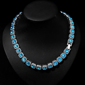 Macro shot of silver hip-hop necklace featuring square lake blue rhinestones on black bust