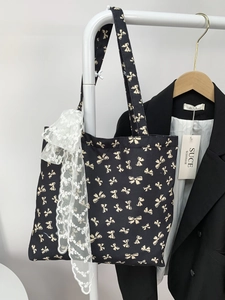 Detail of black canvas tote bag with polka dot bow prints and white floral lace ribbon