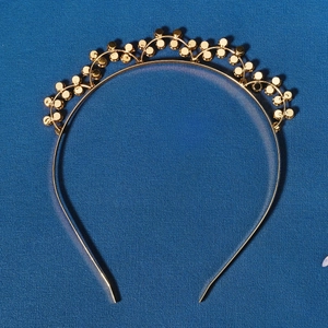 Elegant gold rhinestone headband with wavy metal bead design on a deep blue textured background