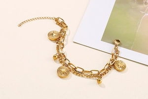 Close-up of gold layered chain bracelet featuring celestial sunburst coin pendants