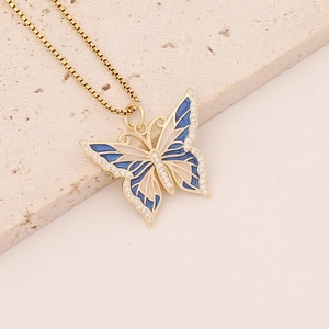 Close-up of gold butterfly pendant with blue enamel and white zircon inlay on stone