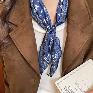 Close-up of navy blue paisley print silk scarf necklace styled with a brown blazer