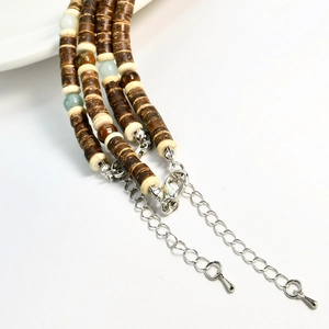 Detail of beaded necklace with brown coconut shells, tiger eye stones and silver chain