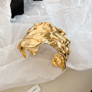 Macro shot of gold wide cuff bracelet with irregular wrinkled lava texture