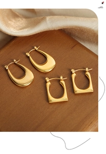 Pendientes geométricos en forma de U bañados en oro sobre elegante tela de raso