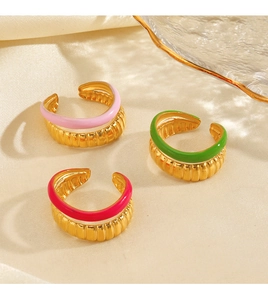 Macro detail of three gold adjustable rings with pink, green, and red enamel finishes
