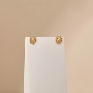 Macro detail of oval gold earrings with engraved flower and sparkling cubic zirconia halo