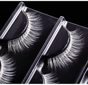 Macro detail of three pairs of dramatic white false eyelashes on a black display tray
