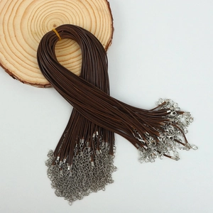 Detailed view of brown waxed cord necklace string with silver lobster clasp on wood