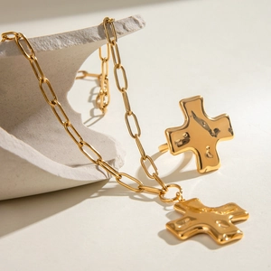 Hammered gold cross pendant necklace and matching ring on a natural stone base
