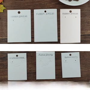 Various textured cardboard earring display cards with hanging holes on wooden background