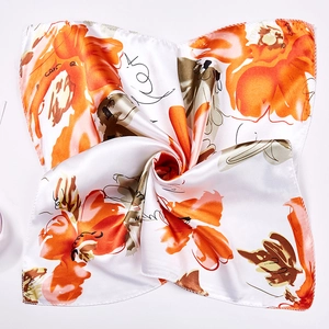 Macro view of silky square scarf featuring vibrant orange flowers and modern chain patterns