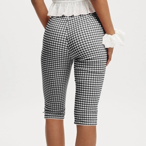 Close-up of black and white plaid cropped pants with delicate white lace hem trim