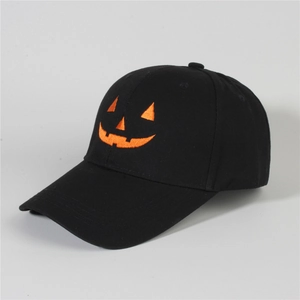 Detail of Jack-o'-lantern pumpkin embroidery on a black denim baseball cap fabric