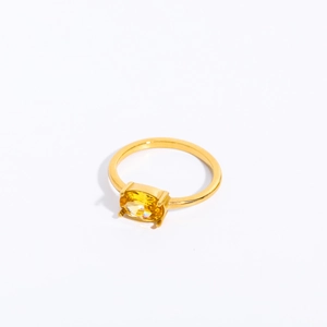 Detail of yellow oval zircon gemstone set in a vacuum-plated golden stainless steel ring