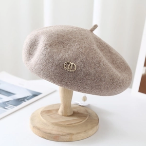 Detailed texture of oatmeal wool tweed beret featuring a golden double ring ornament