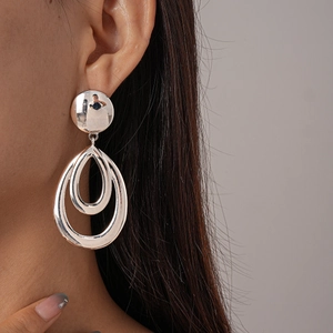 Detail view of silver hollow waterdrop earrings worn by a model with smooth metallic finish