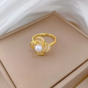 Macro detail of gold flower ring with center pearl and diamond accents on petals