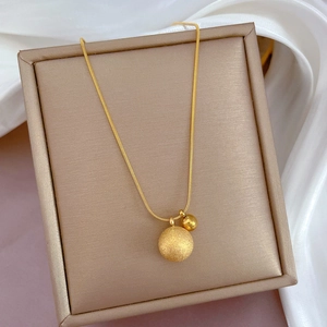 Detailed close-up of dual gold beads with matte and polished finishes on silk background