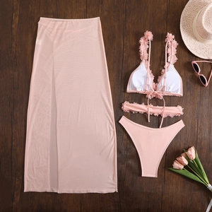 Flat lay of pink three-piece bikini set with 3D floral accents and mesh long sarong