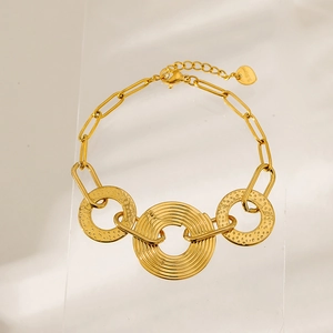 Detail of gold stainless steel bracelet showing hammered texture and concentric ring pendants