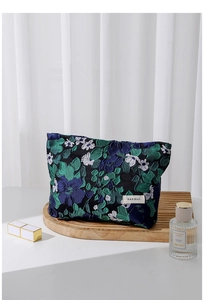 Detail of floral jacquard fabric on navy cosmetic bag with brand label and fine texture