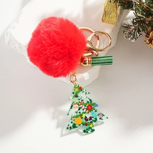 Detail of Christmas tree keychain with red faux fur pompom and green tassel on stone base