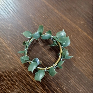 Rustic farmhouse napkin ring with green leaves on gold metal ring over dark wood