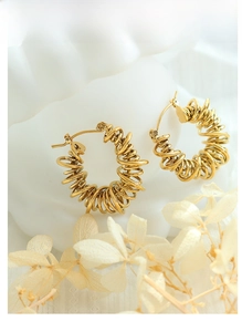 Close-up of golden spiral U-shaped earrings with a metallic finish on a white background