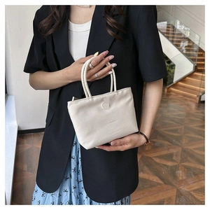 Sac seau en nylon crème chic avec doubles poignées porté par un mannequin pour la taille