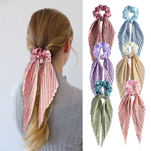 Detail showing pleated satin hair scrunchies with long ribbons and golden polka dots