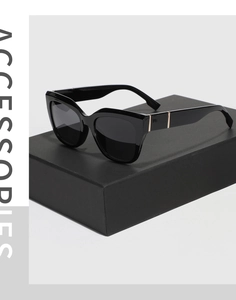 Close-up of black cat eye sunglasses with gold hinge detail on a premium display box