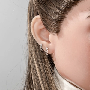 Silver hoop earrings with star pendant and chain on model ear, minimalist style