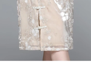 Detailed view of champagne lace embroidery and traditional Chinese frog buttons on a qipao