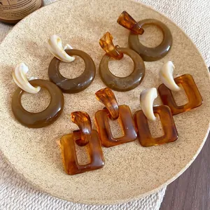Retro amber resin hoop earrings and geometric studs on a premium beige jewelry tray