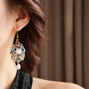 Detail of vintage enamel earring with floral patterns and baroque pearl on model