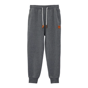 Detail of dark gray joggers featuring a white drawstring waist and leather patch accent