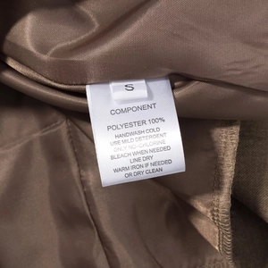 Détail de l'étiquette de taille S et de la doublure 100% polyester d'une robe marron