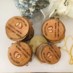Detail of wooden Merry Christmas Mommy and Daddy ornament with infant footprints