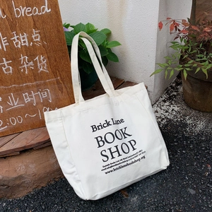 Detail of Brick Lane Book Shop print on off-white canvas tote bag in outdoor setting